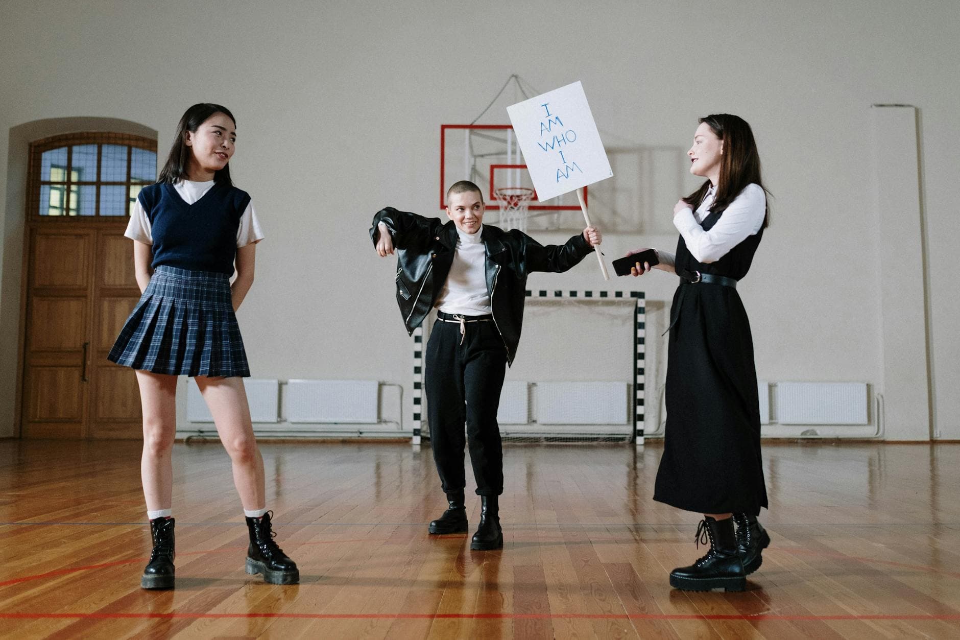 Diverse students protesting indoors holding signs with messages in a school gym.