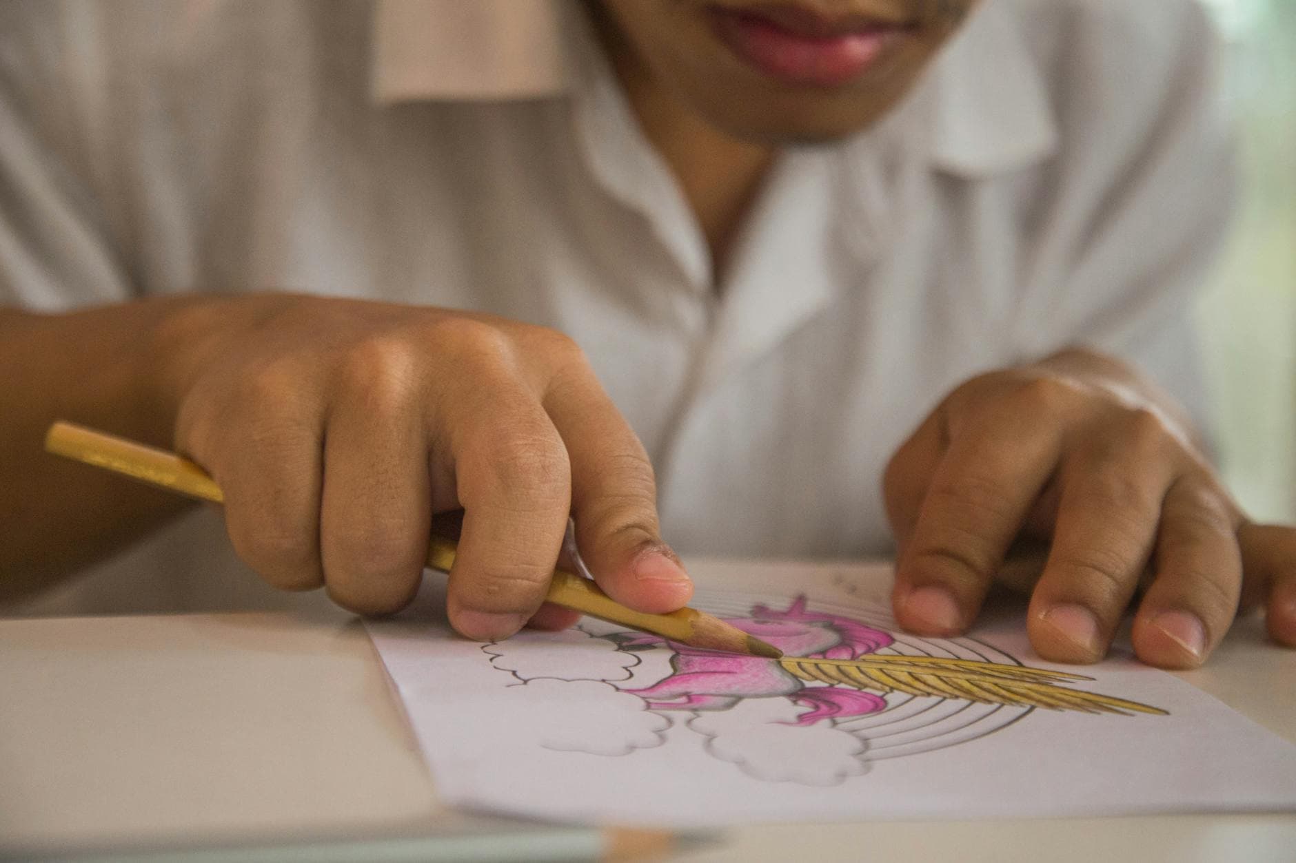 Close-up of a child deeply engaged in coloring with pencil crayons, showcasing creativity.
