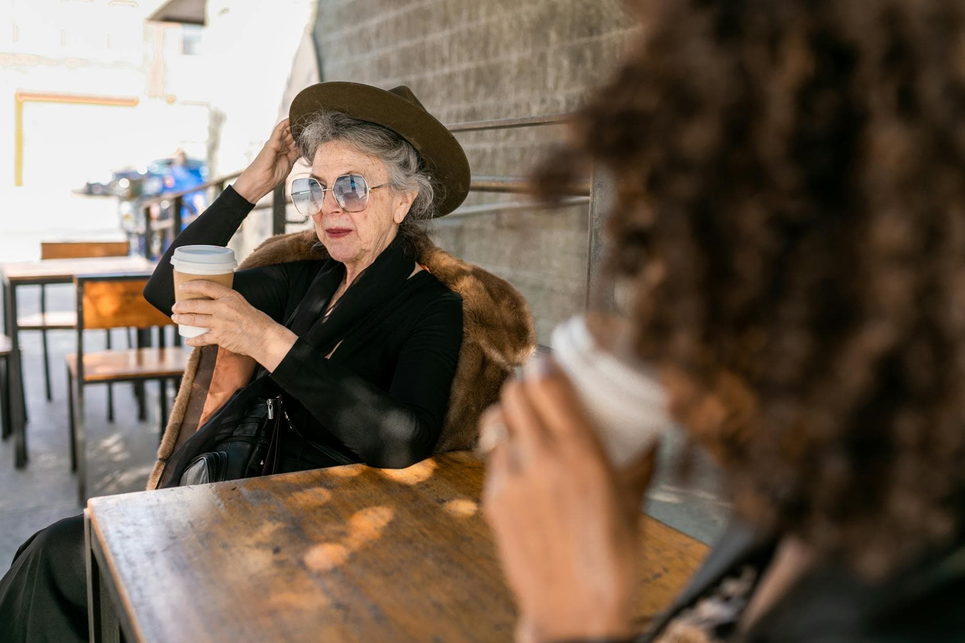 Stylish senior woman sipping coffee outside in a relaxed setting.