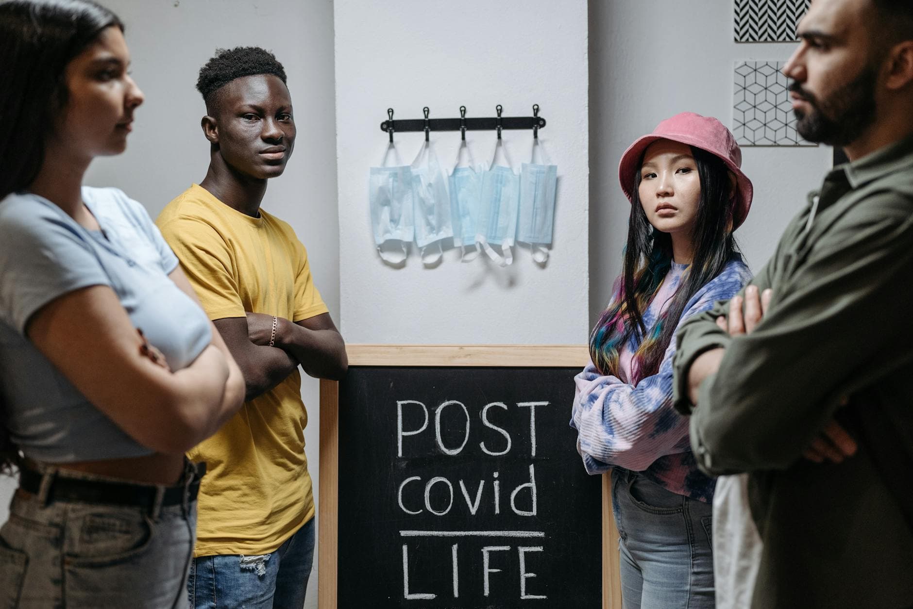 A group of diverse individuals standing around a chalkboard with 'Post Covid Life' written on it.