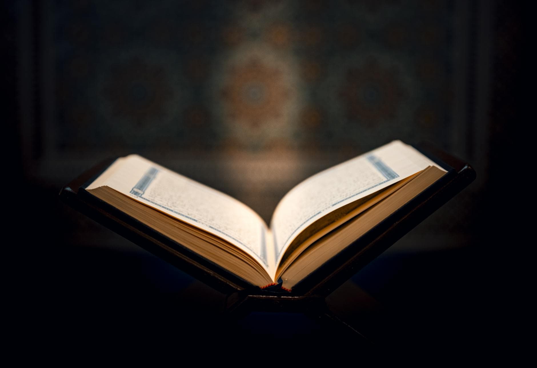Open Quran on a wooden stand against a decorative background, capturing a spiritual ambiance.