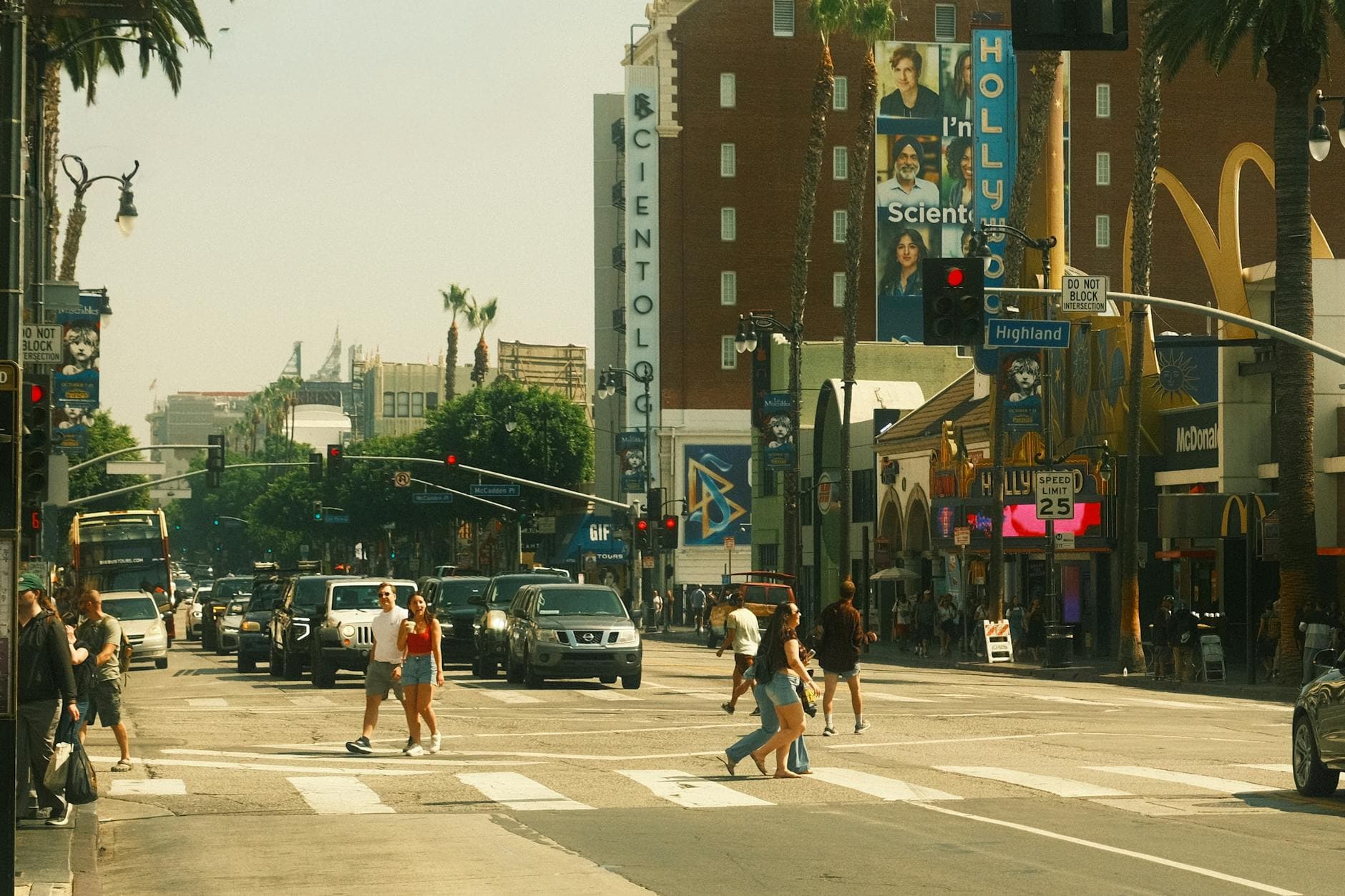 Vibrant street view of Hollywood Boulevard with pedestrians and traffic at a crossroads.