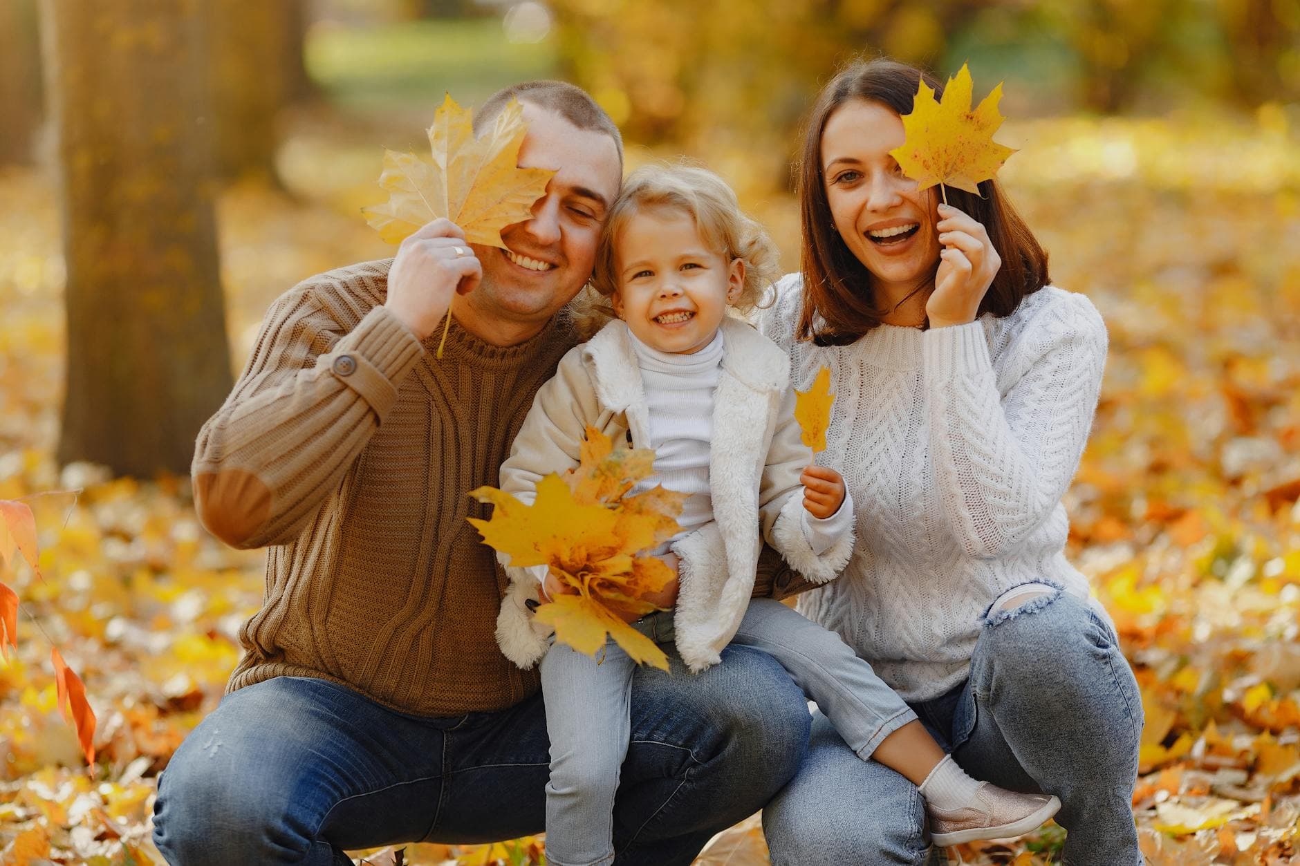 Family having fun with autumn leaves in a park, capturing joyful and warm moments.