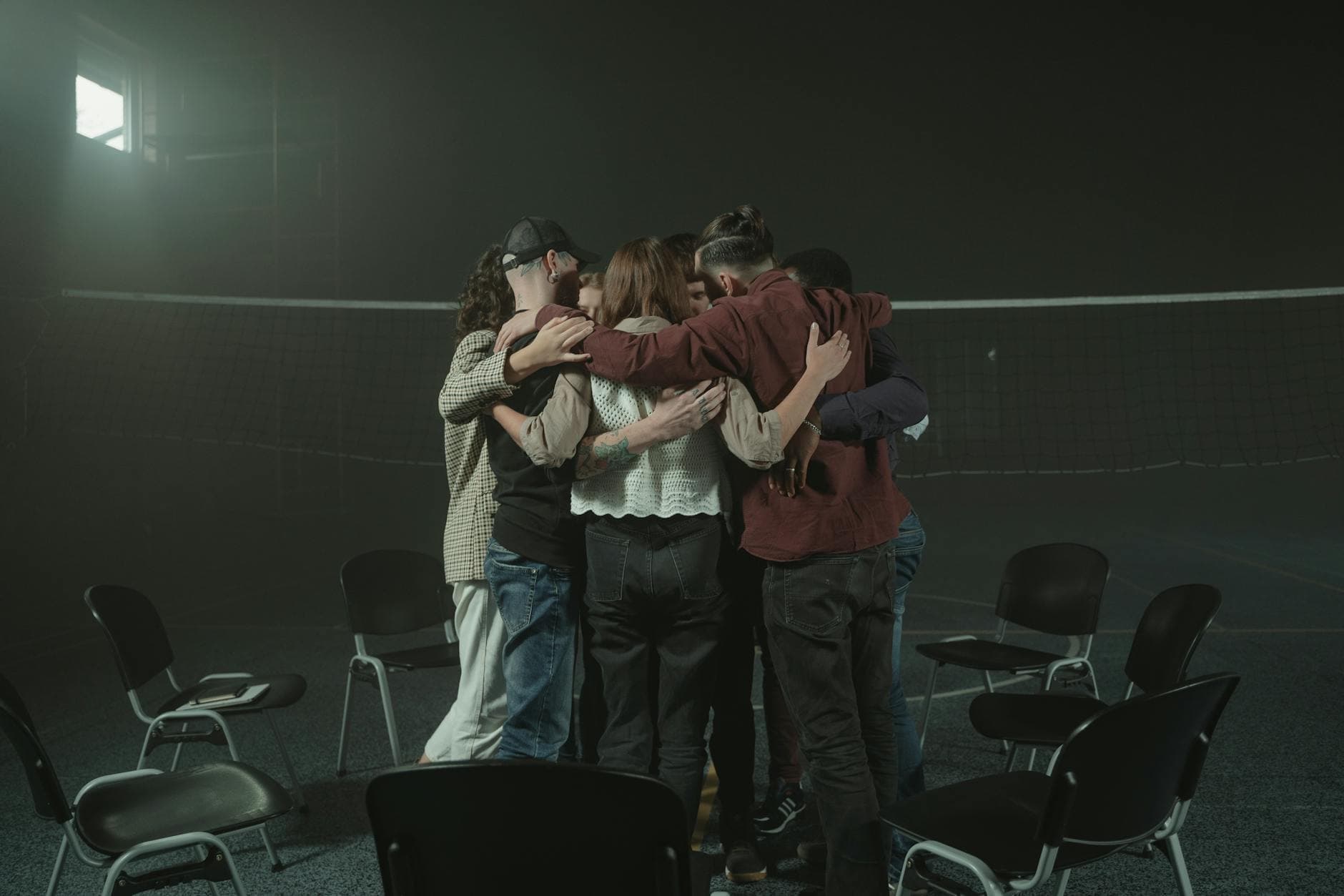 A group of people embracing in a large room, symbolizing unity and emotional support.