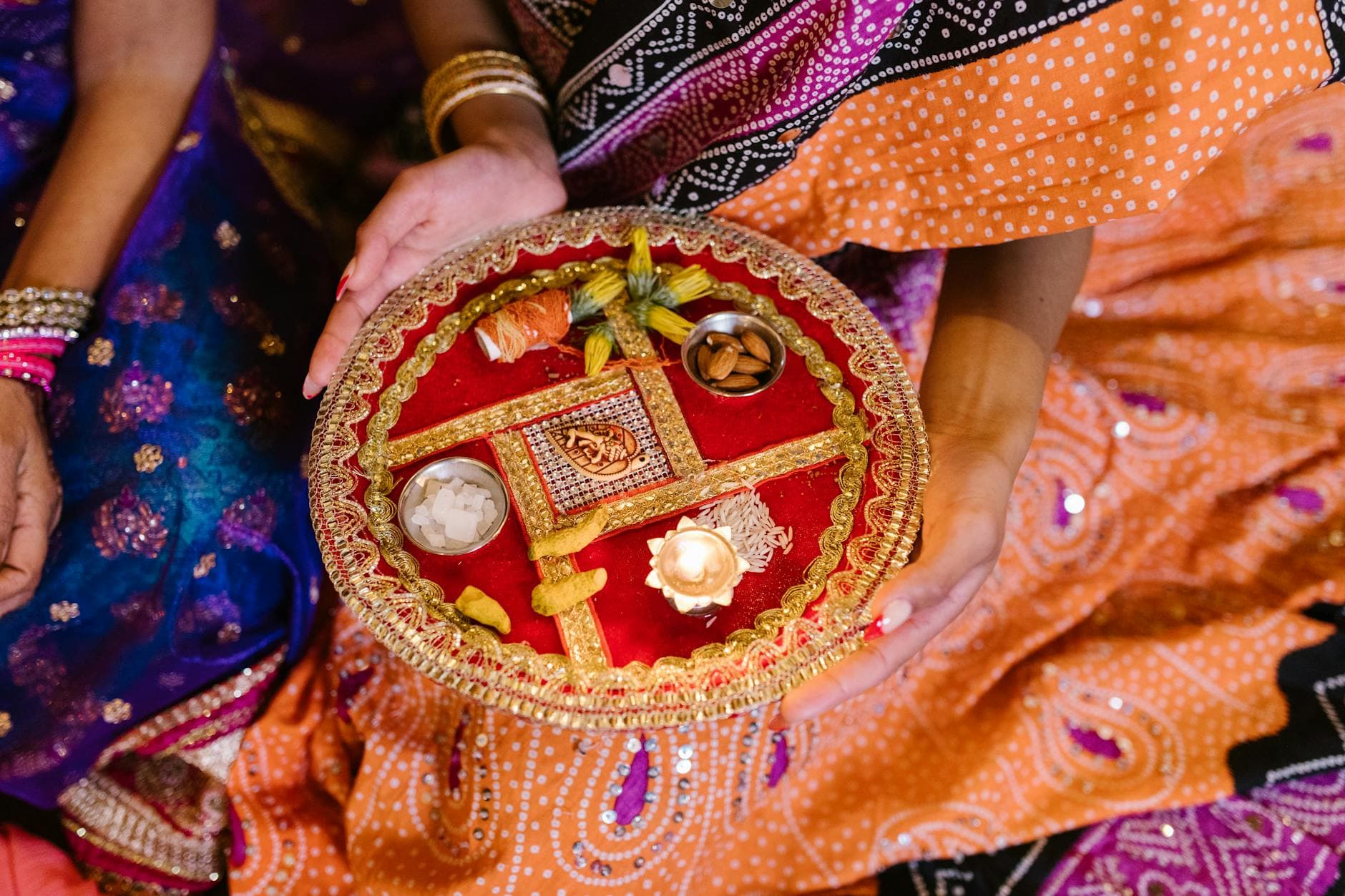 A vibrant festival plate with offerings held by a woman in traditional attire.