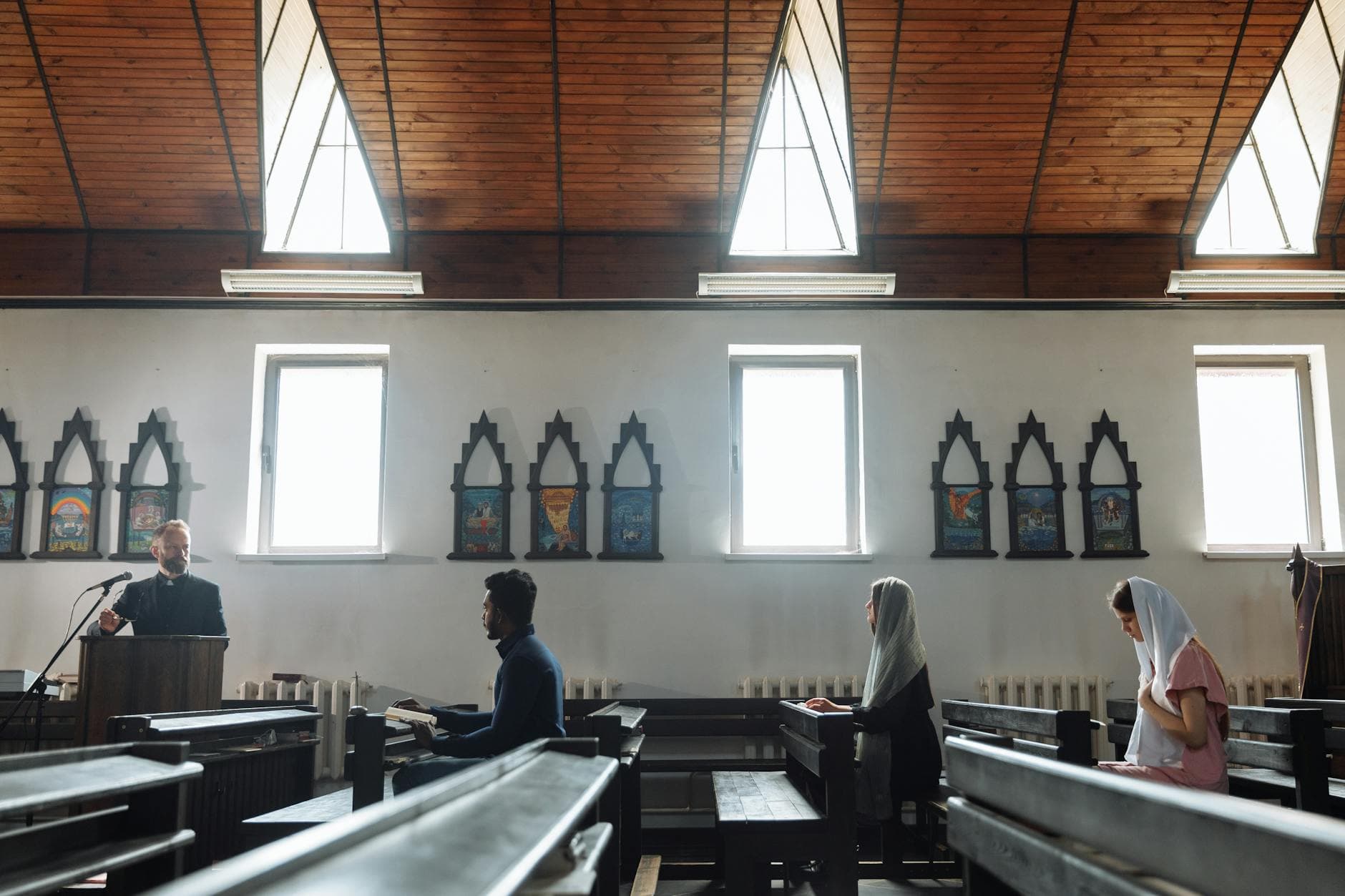 A serene church interior with people praying and a priest presiding from a pulpit.