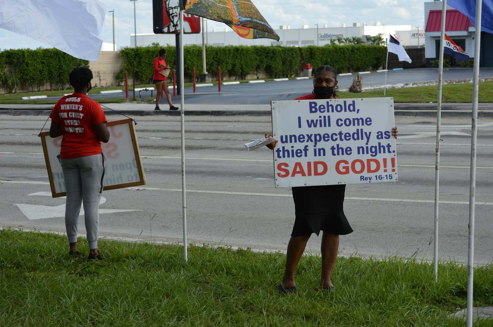 Two people holding religious signs on a street discussing Revelation 16:15.