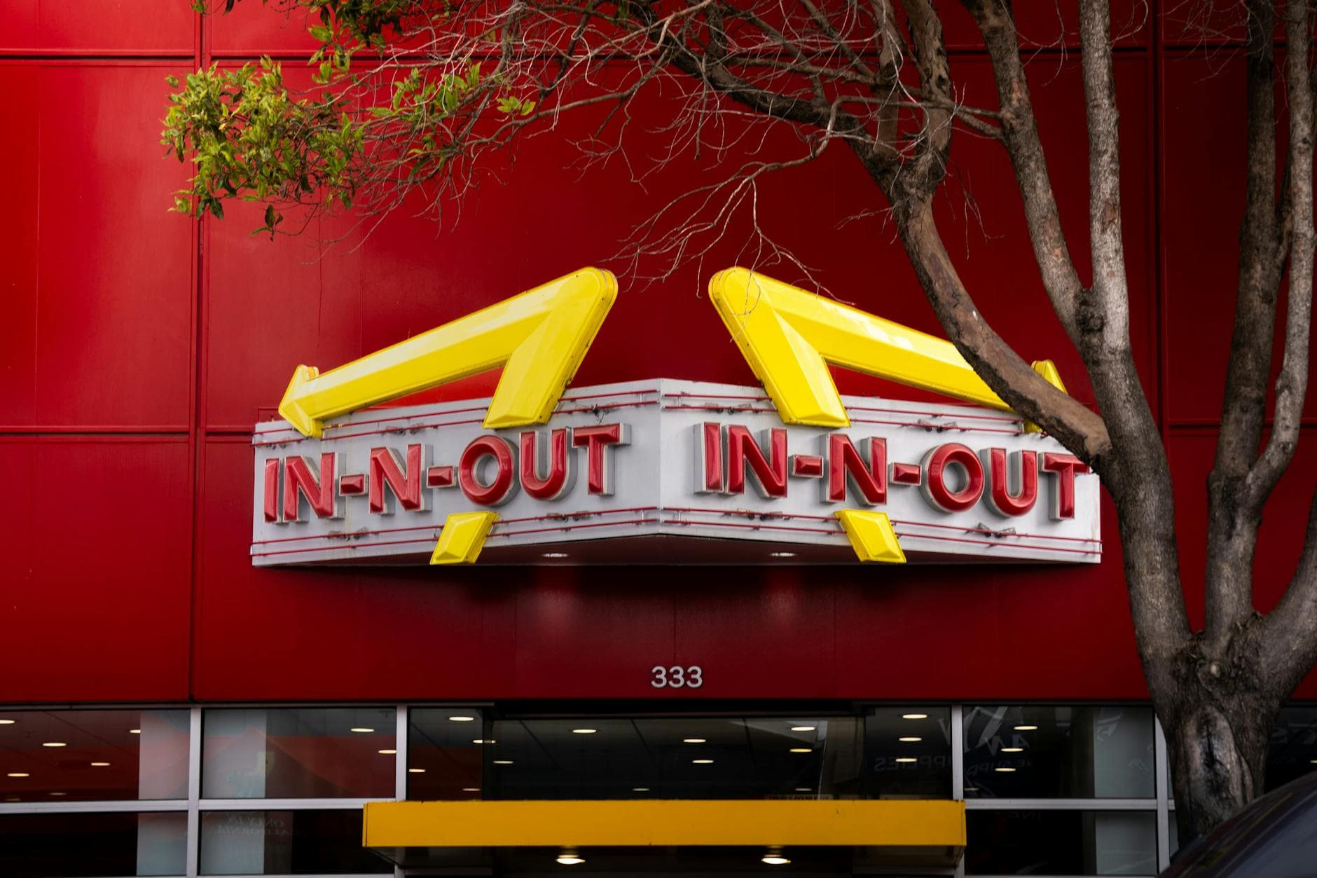 Iconic In-N-Out Burger sign with bold red background and trees in the foreground.