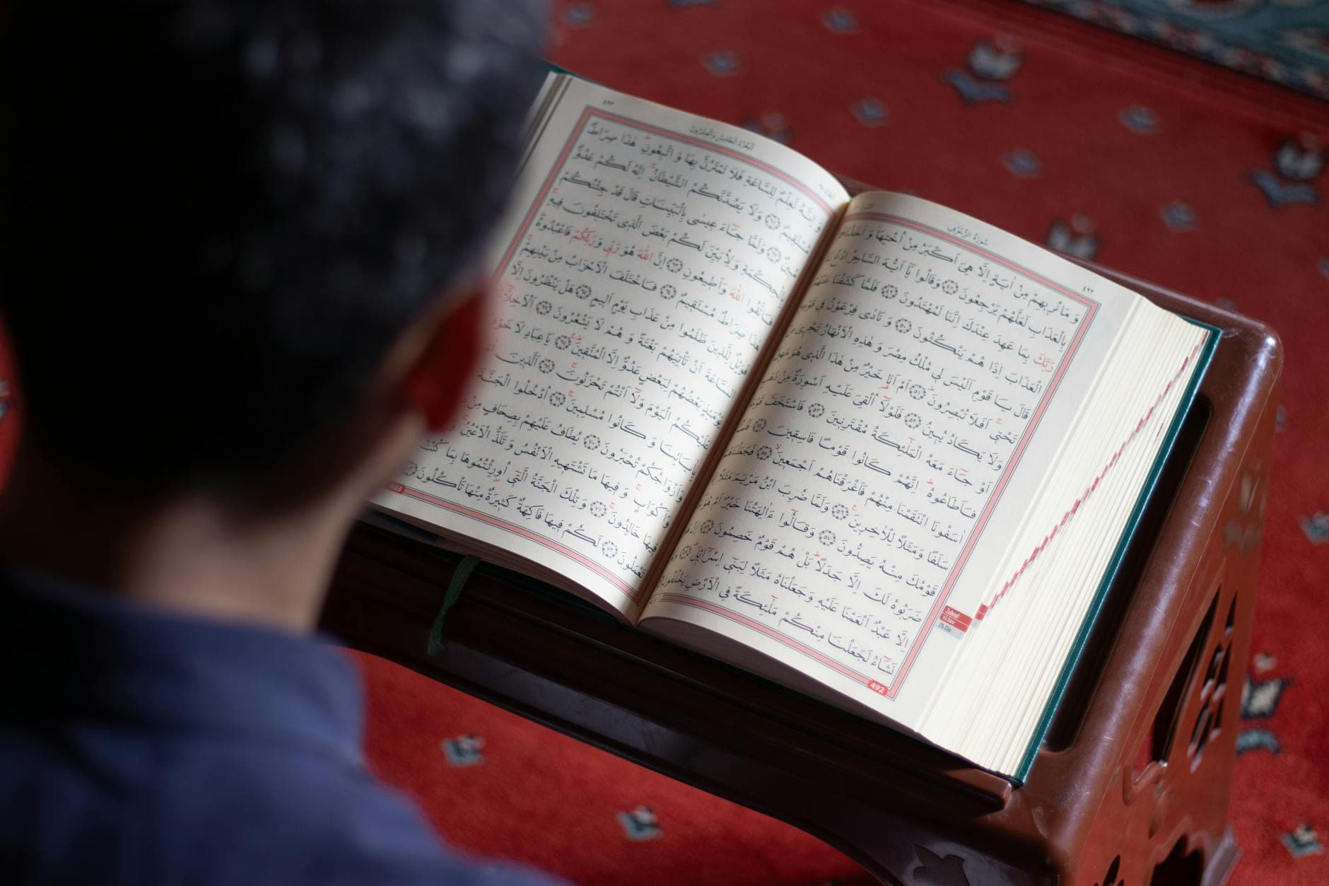 A man reads the Quran, highlighting Islamic faith in a mosque ambiance.