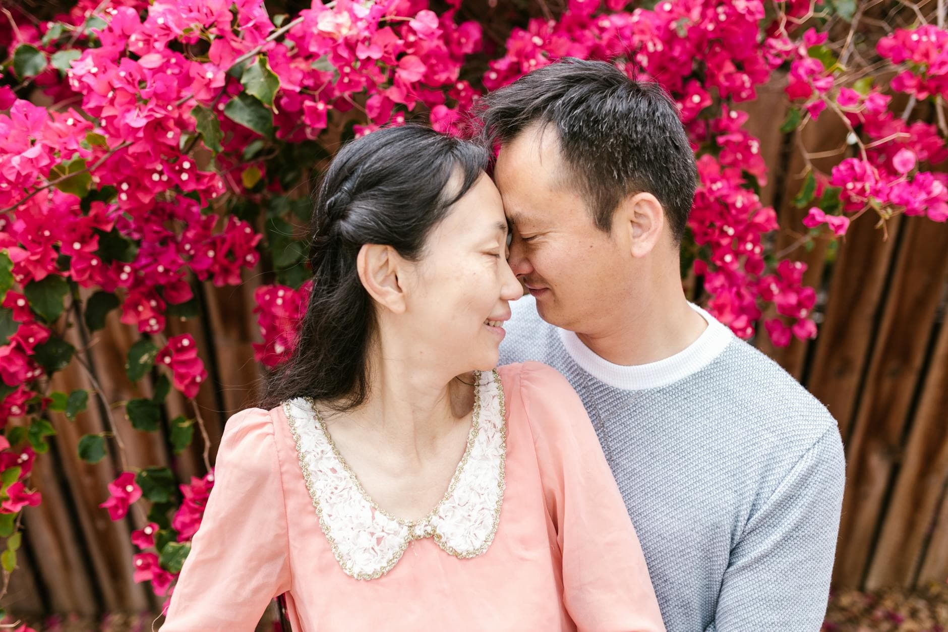 A couple joyfully sharing an intimate moment surrounded by vibrant flowers.