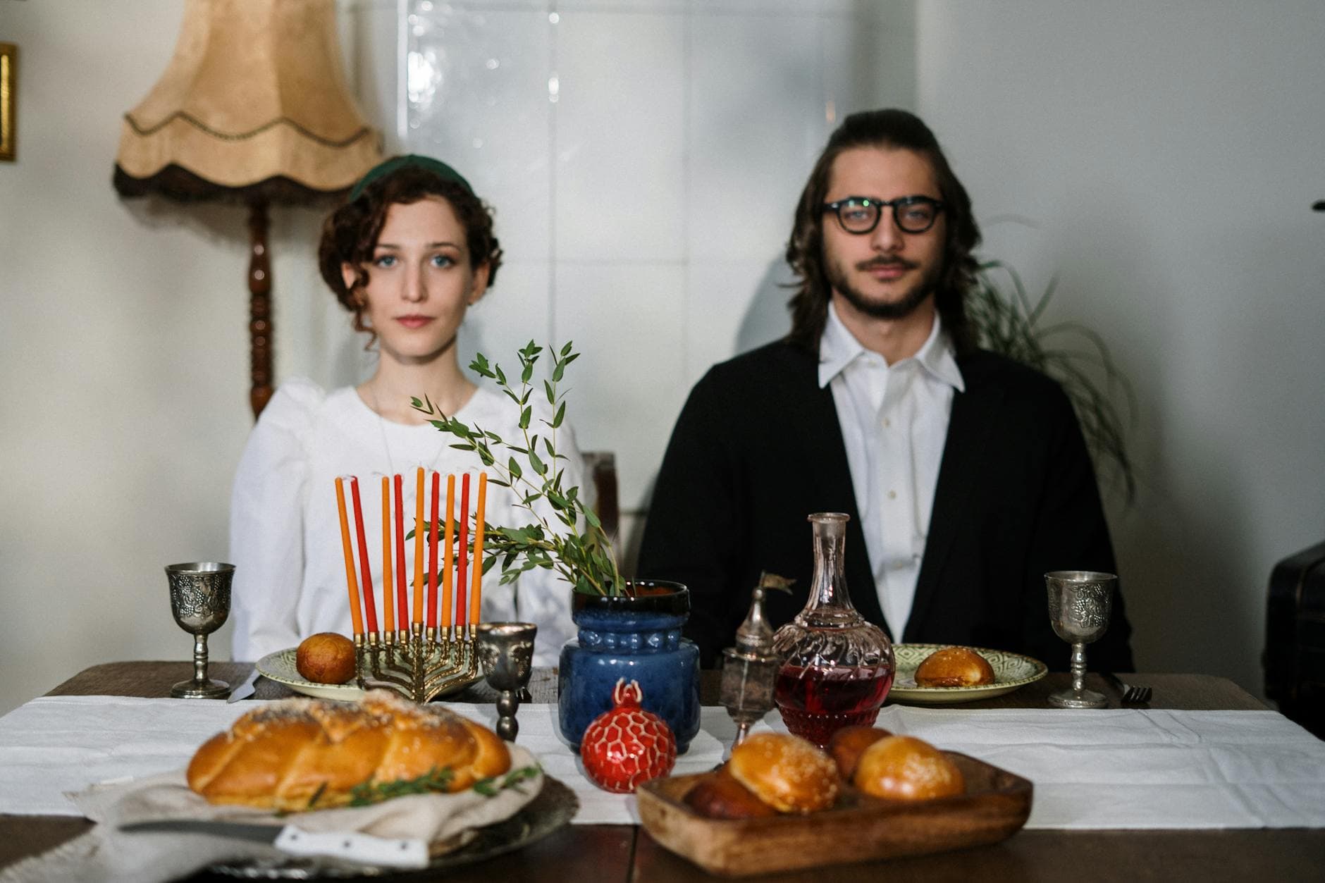 A Jewish couple celebrates Shabbat with traditional food and menorah at home.