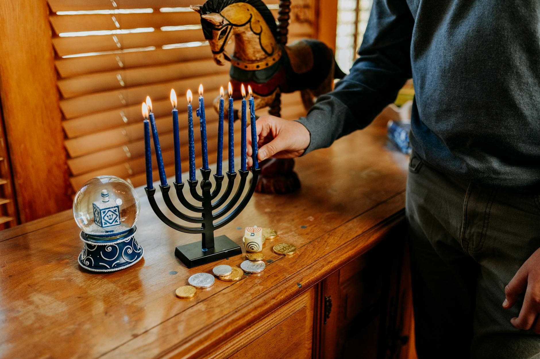 A lit menorah with dreidel and gelt on a wooden table during Hanukkah celebration.