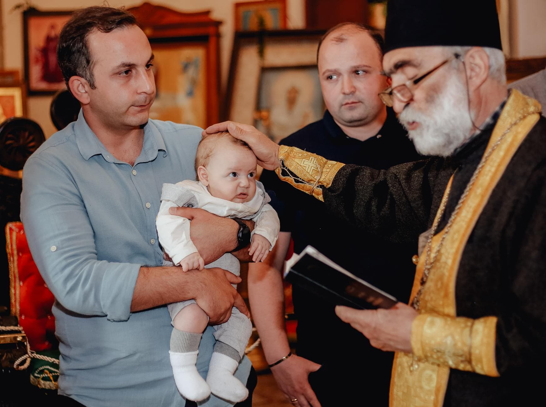 A baby is baptized by a priest in a traditional church ceremony, showcasing a spiritual rite.