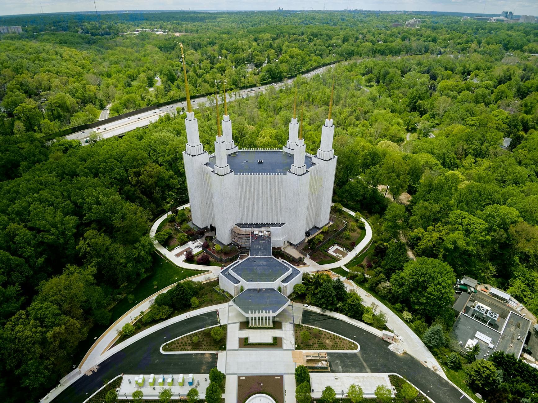 Aerial view of Washington D. C. Temple with white marble building and ornamental spires located amidst abundant green park