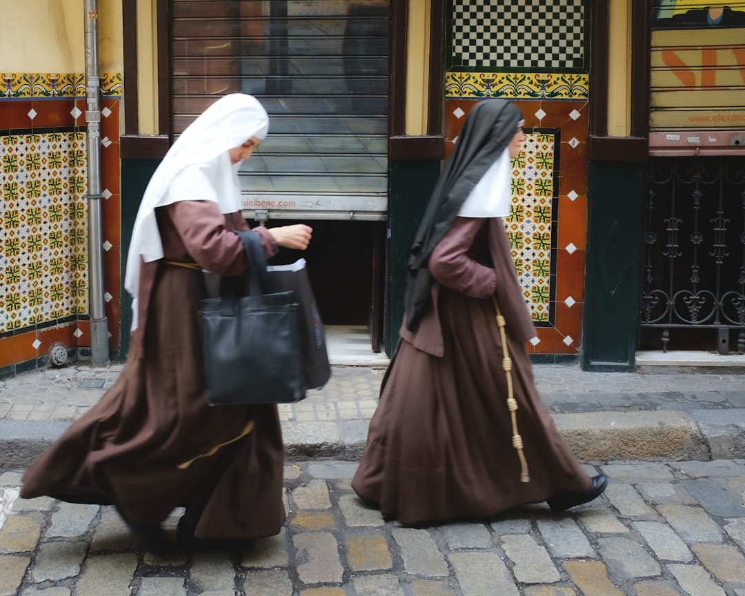 Two nuns walking on a cobblestone street.