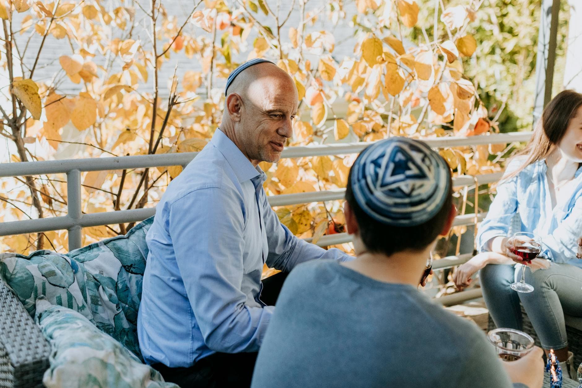 A Jewish family enjoying a festive outdoor gathering during fall, sharing talks and wine.
