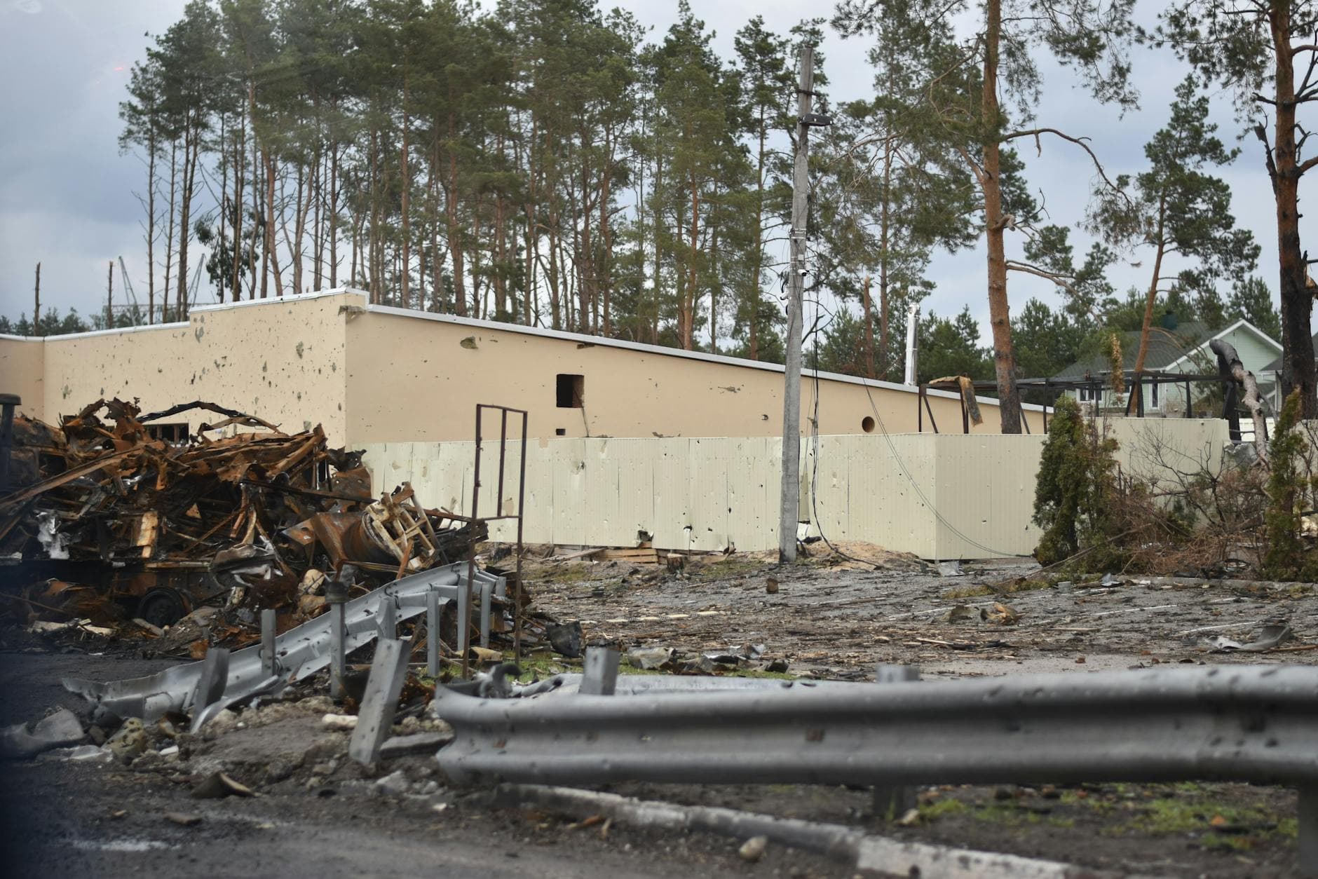 A war-torn scene featuring a destroyed building, debris, and surrounding trees.