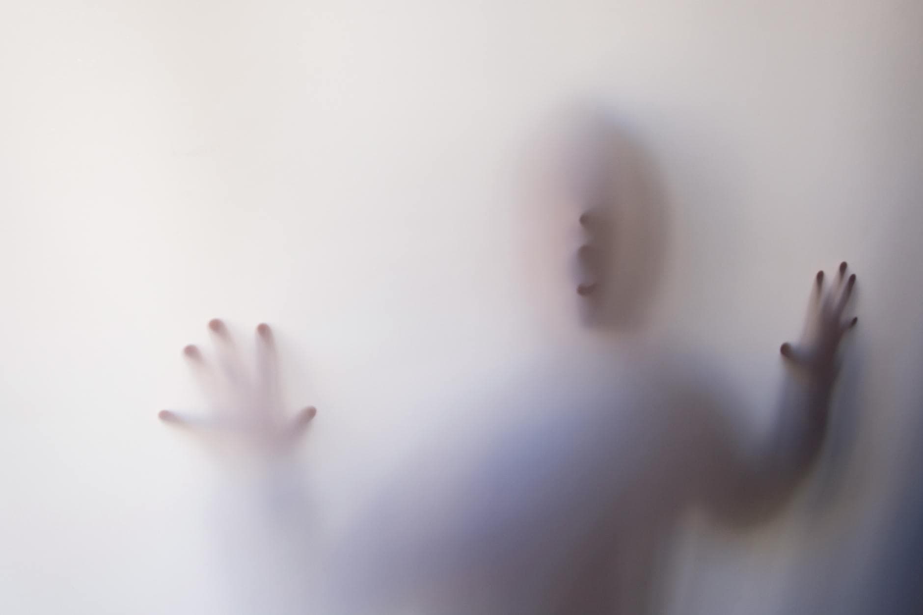 Eerie silhouette of a person pressing against a white curtain, creating a mysterious atmosphere.