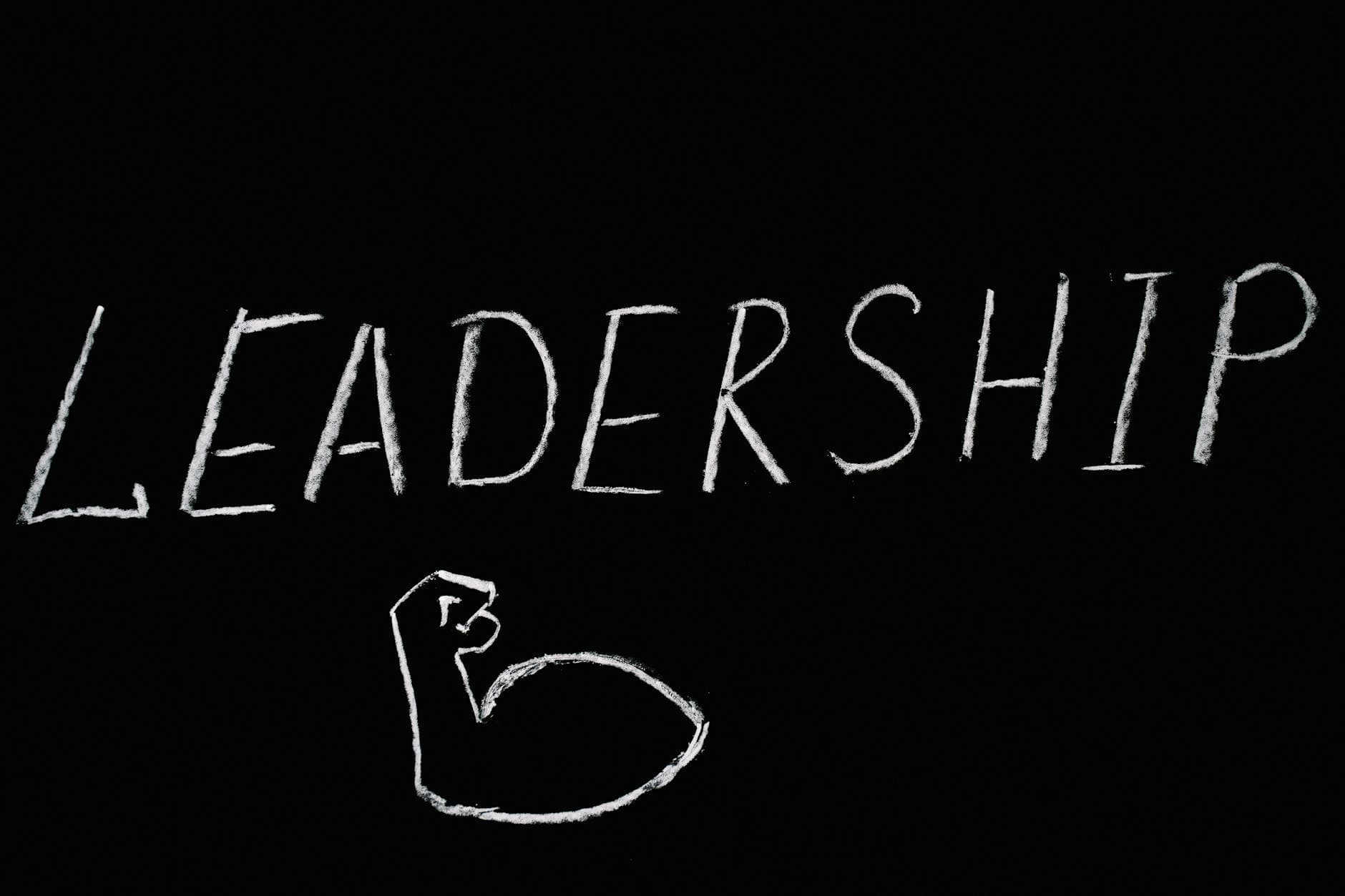 Chalkboard art showcasing the word 'Leadership' and a drawn muscle symbolizing strength.