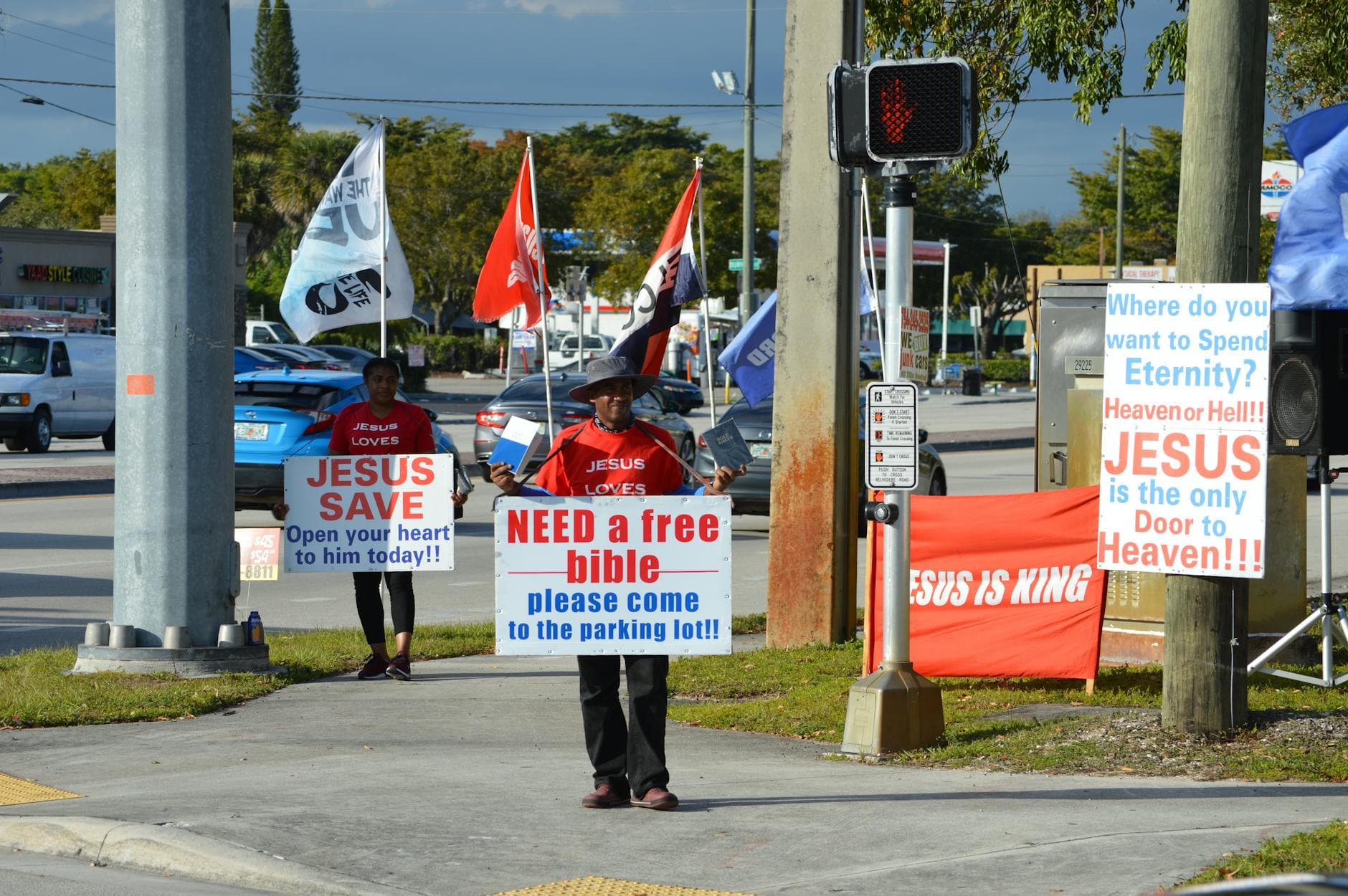People handing out free Bibles with religious signs and flags on a city street.