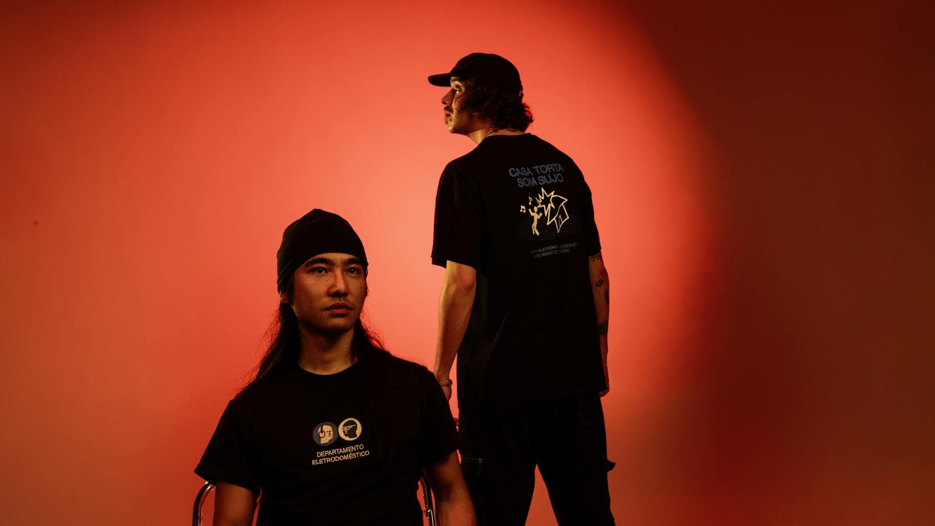 Dramatic studio portrait of two people against a vibrant red background.