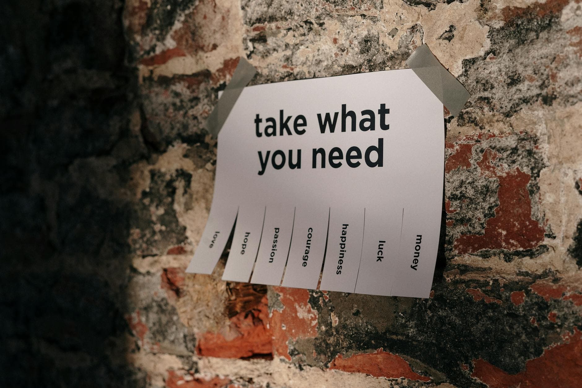A motivational note offering positive qualities taped to a brick wall.