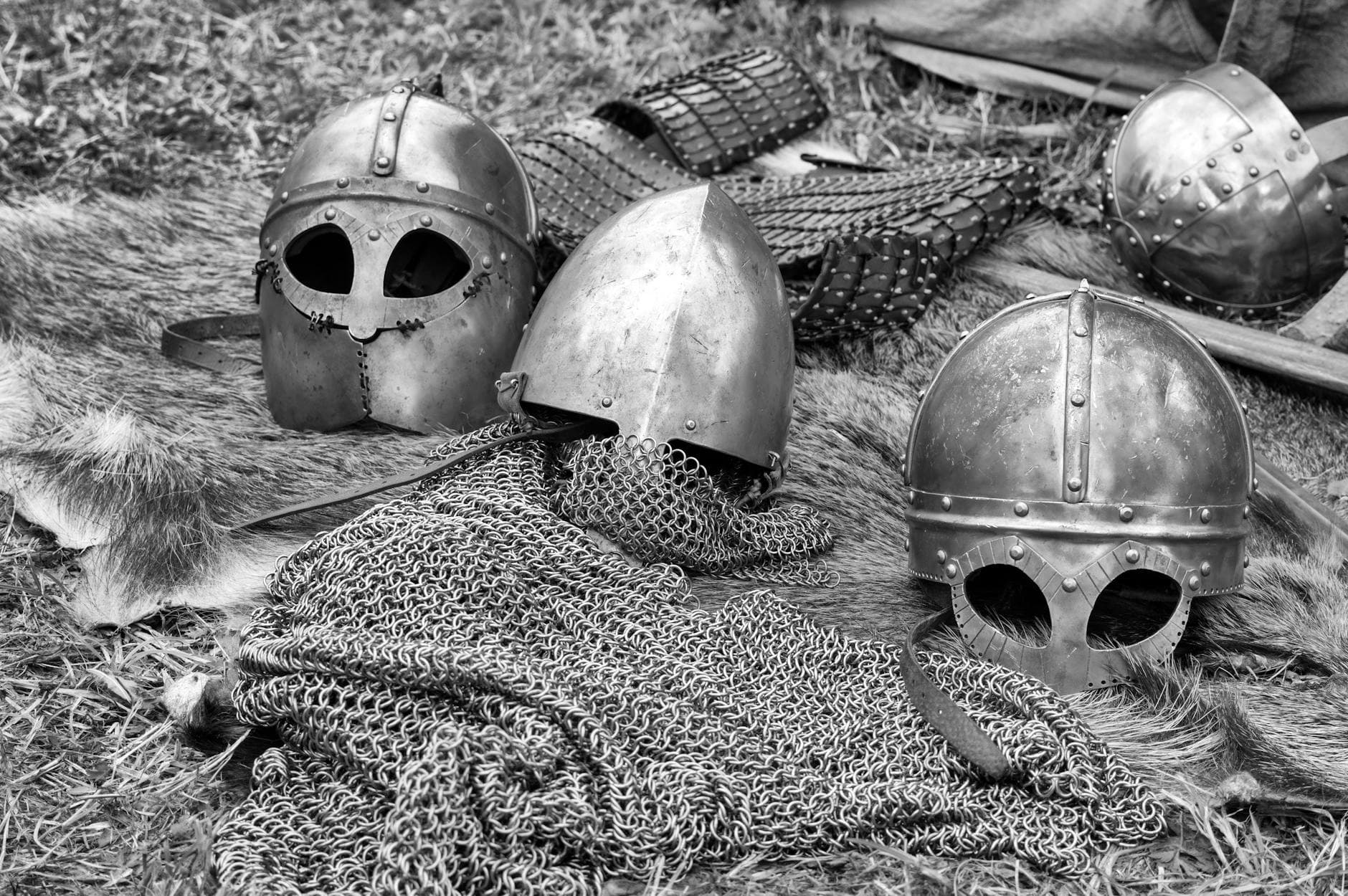 Close-up of historical medieval helmets and armor in black and white.