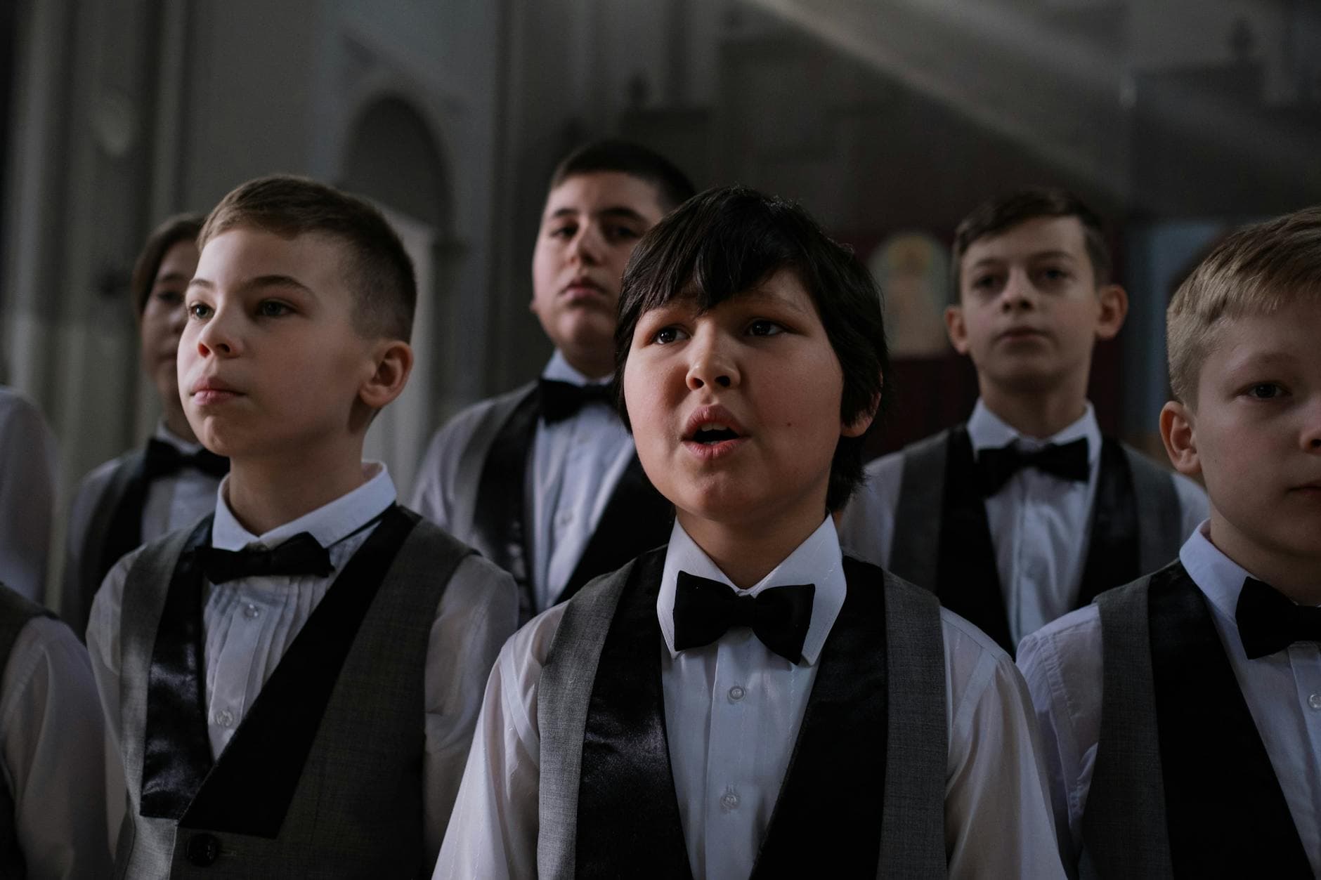 A group of young boys performing in a church choir wearing formal attire.