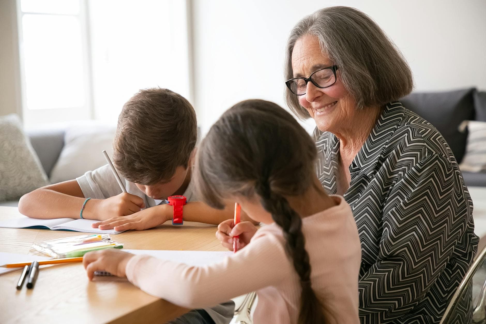 Grandmother enjoying quality time drawing with her grandchildren indoors.