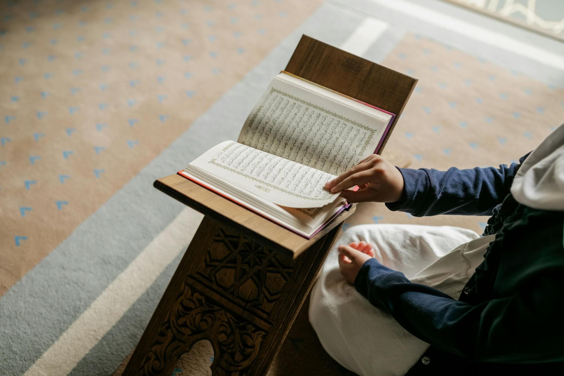 A young Muslim girl reading the Quran indoors, symbolizing devotion during Ramadan.