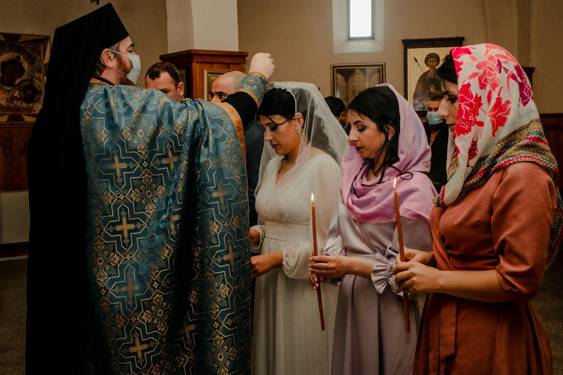 A traditional Orthodox wedding ceremony with priest and candles inside a church.