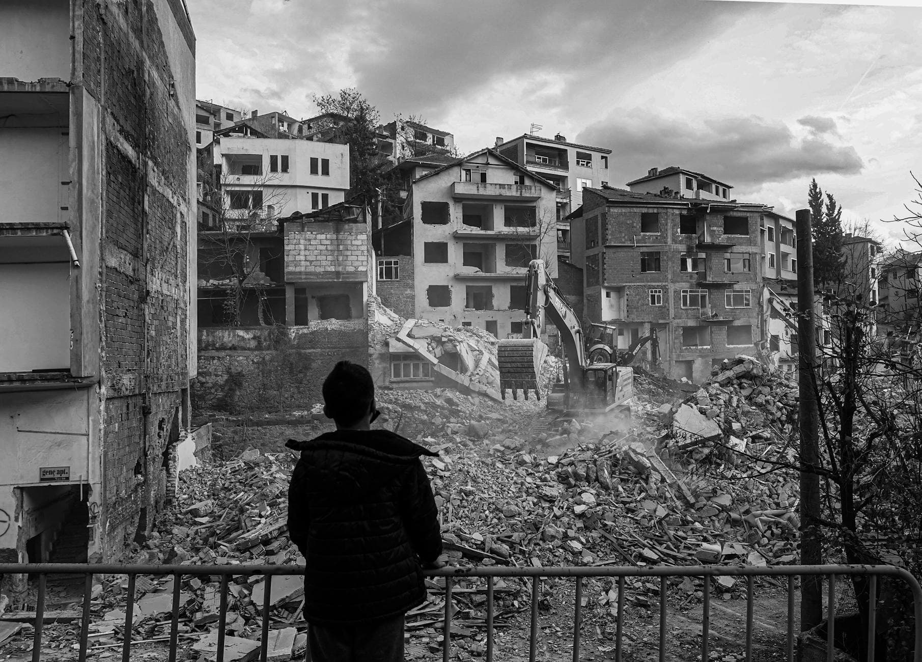 A person watches the demolition of dilapidated urban buildings.