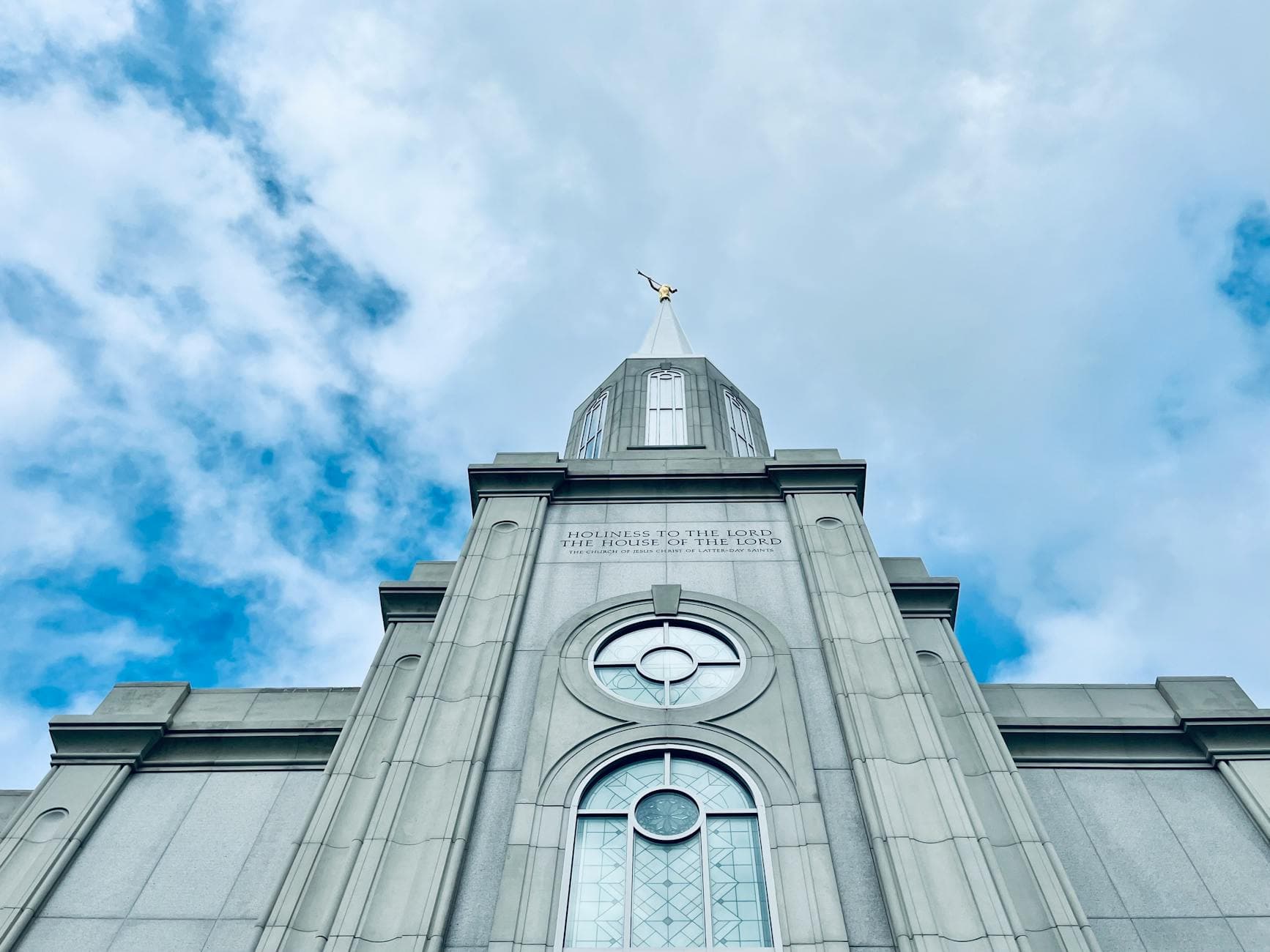 Low angle view of the St. Louis Missouri Temple against a cloudy sky, showcasing religious architecture.