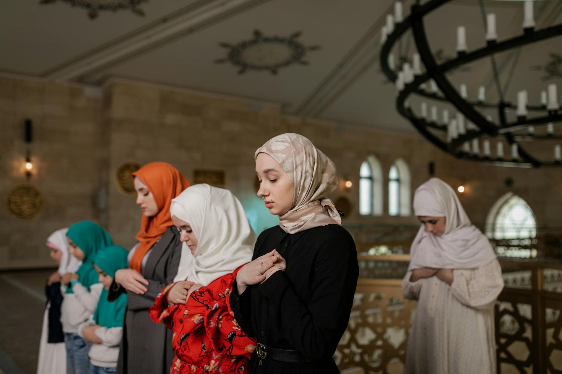 A group of women in hijabs praying inside a beautifully decorated mosque during Ramadan.
