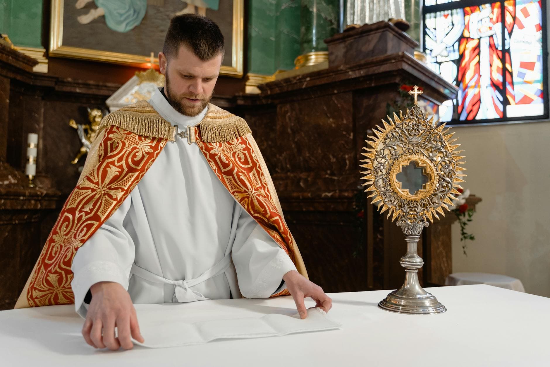 A priest preparing the altar with a monstrance in a Catholic church, highlighting sacred rituals.